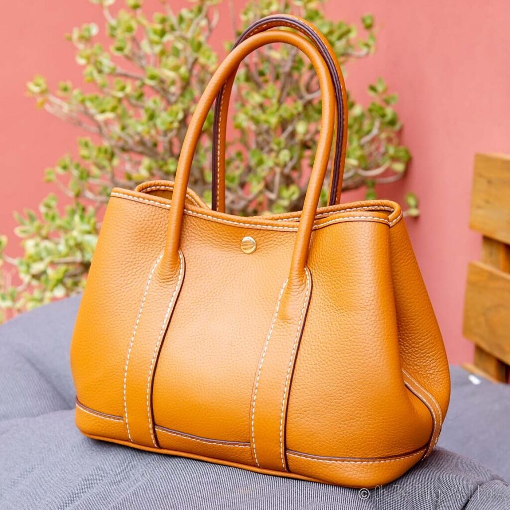 A tan leather handbag sitting on a couch.